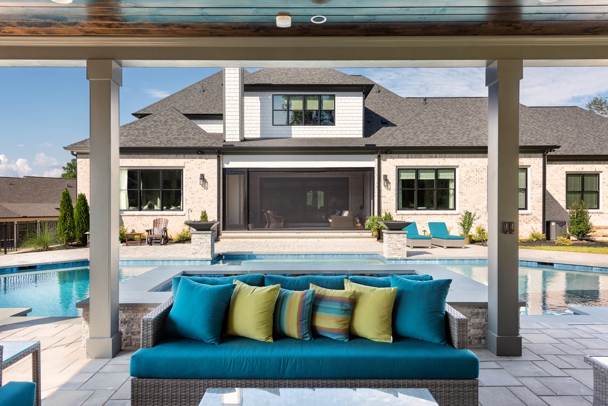 Covered poolside daybed looking across the water toward the home's retractable screen wall, Braselton GA