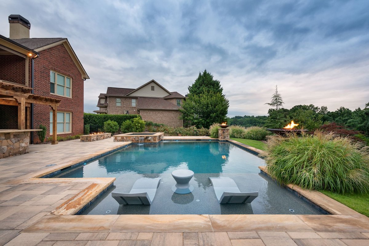 In-pool loungers on the sun ledge at dusk beside the brick home, Traditions of Braselton, Jefferson GA